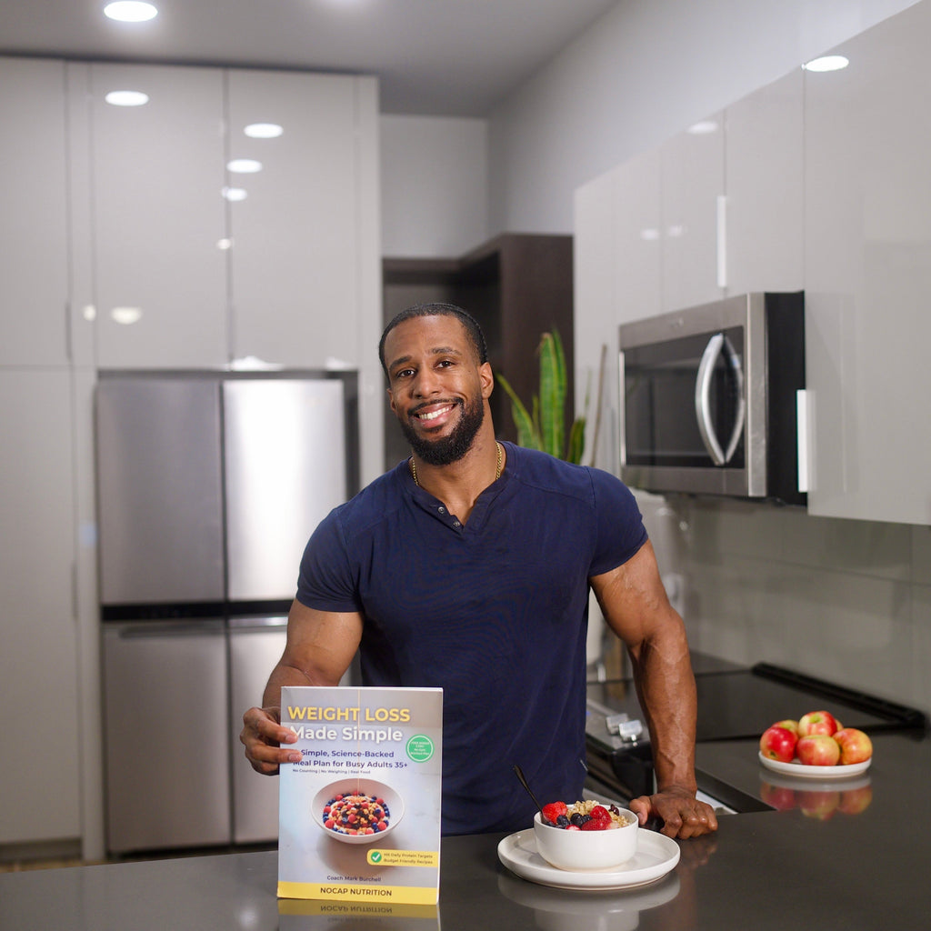 Coach Mark Burchell holding the Weight Loss Made Simple book next to a Greek yogurt breakfast bowl