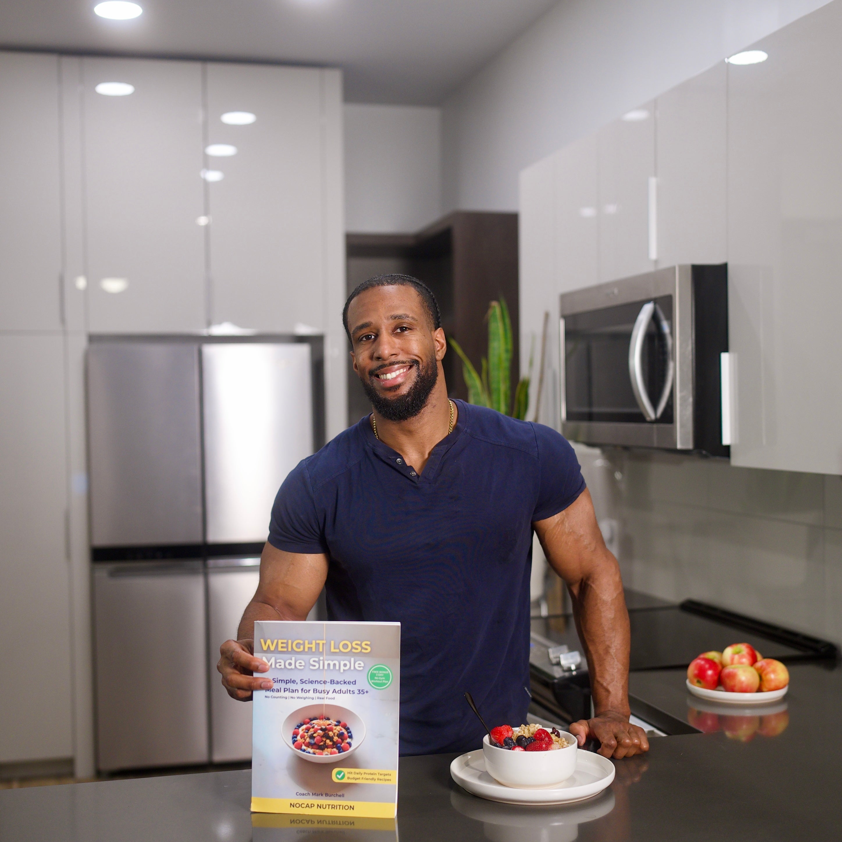 Coach Mark Burchell holding the Weight Loss Made Simple book next to a Greek yogurt breakfast bowl